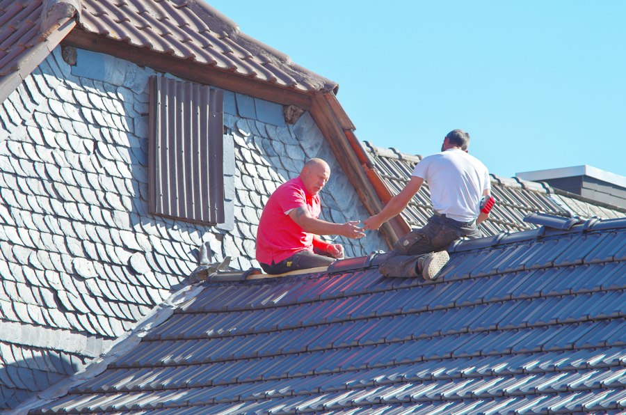 Two roofers working together on a slate roof