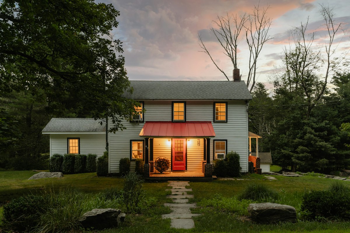 White farmhouse with a red awning at dusk